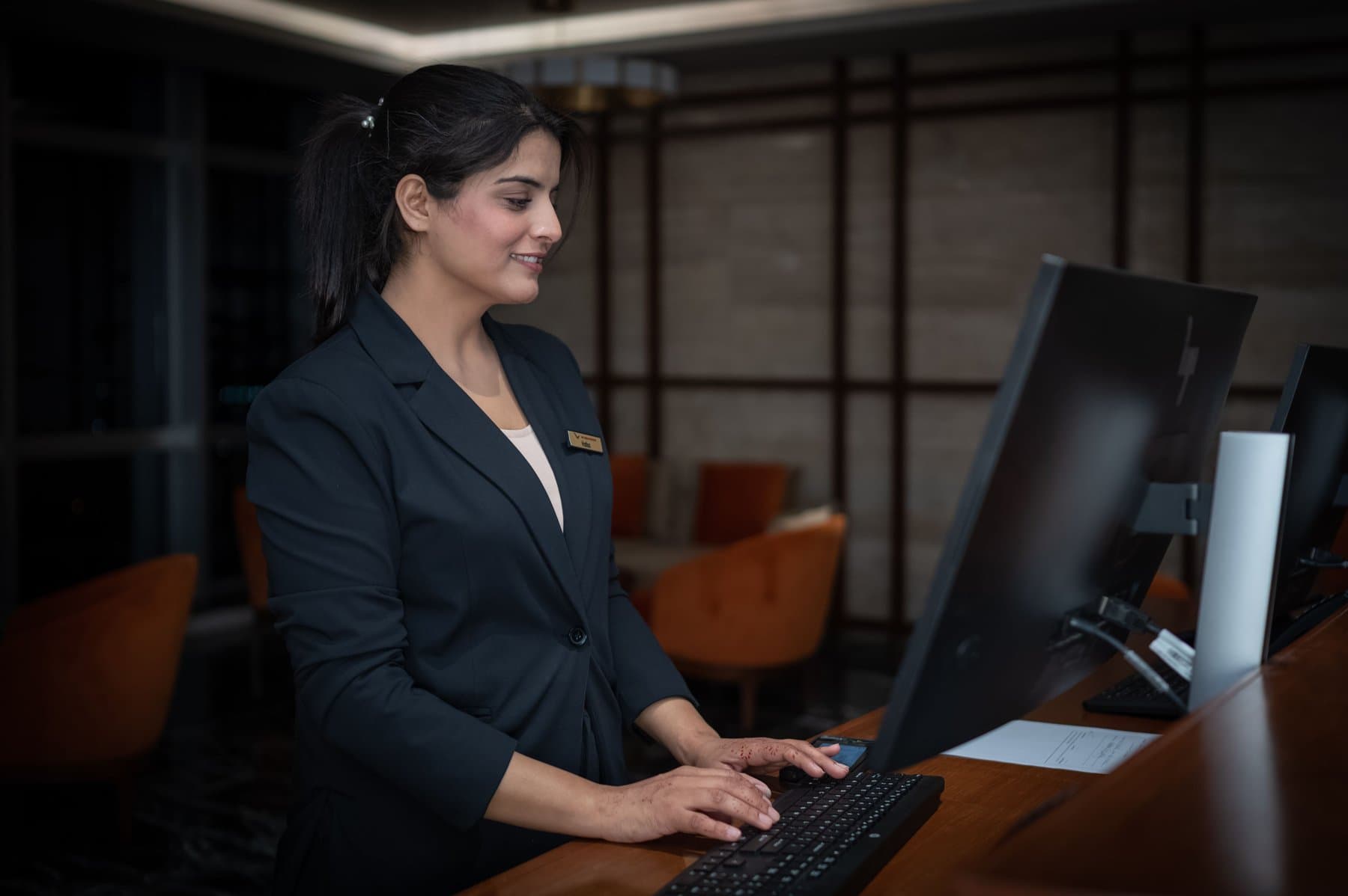 Una receptionist d'albergo al bancone mentre guarda lo schermo di un computer