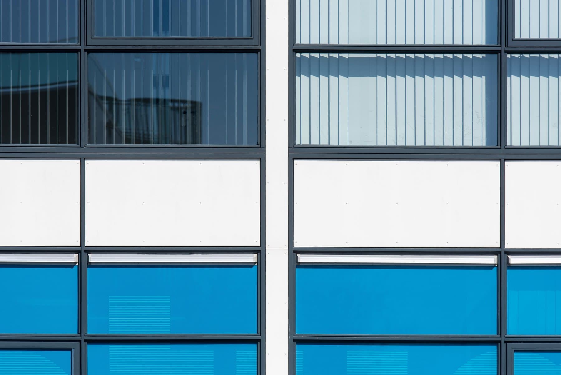 Close-up detail of a modern office building facade, with blue windows and white panels