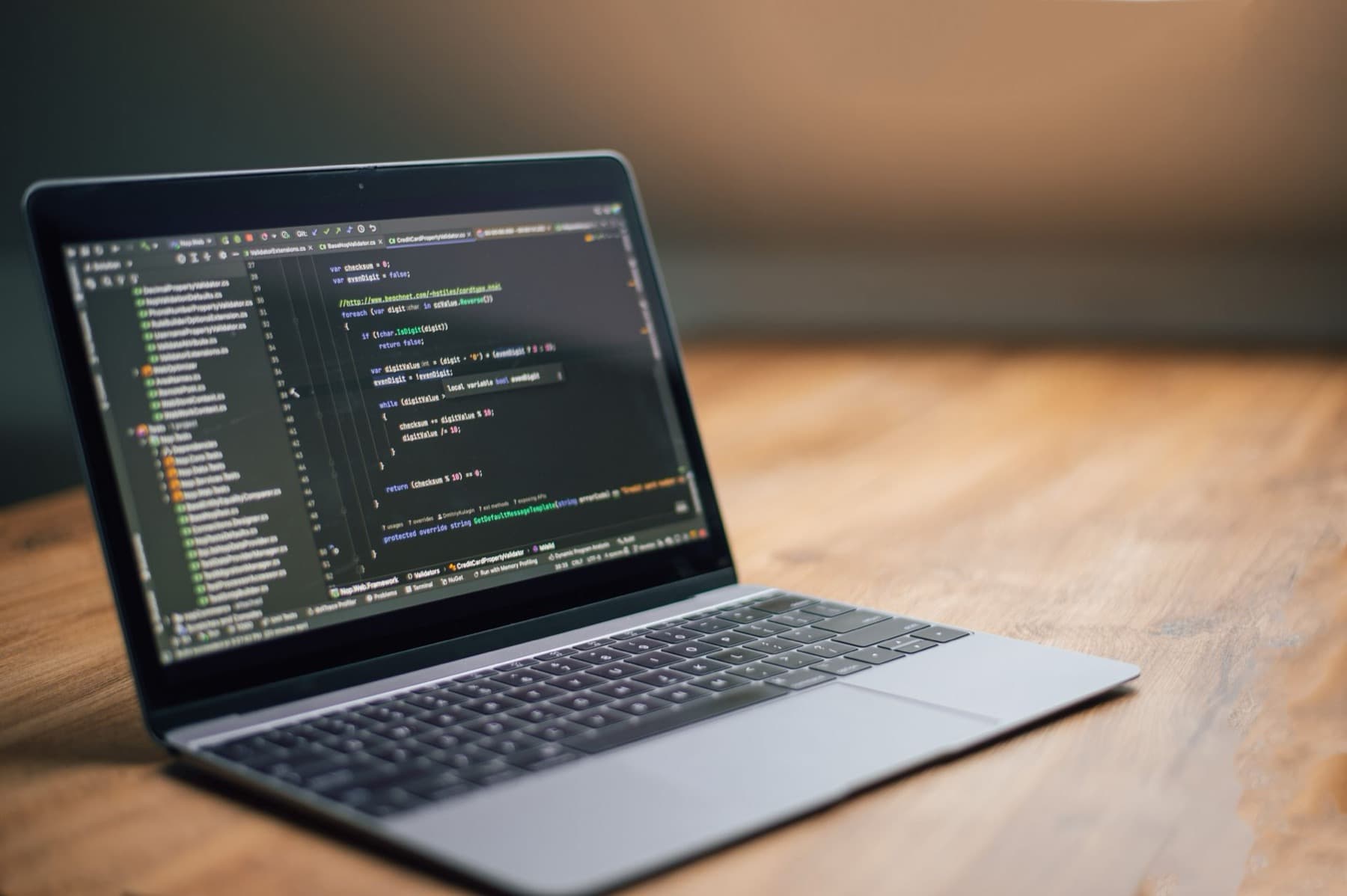 An open laptop showing a code editor, resting on a wooden desk