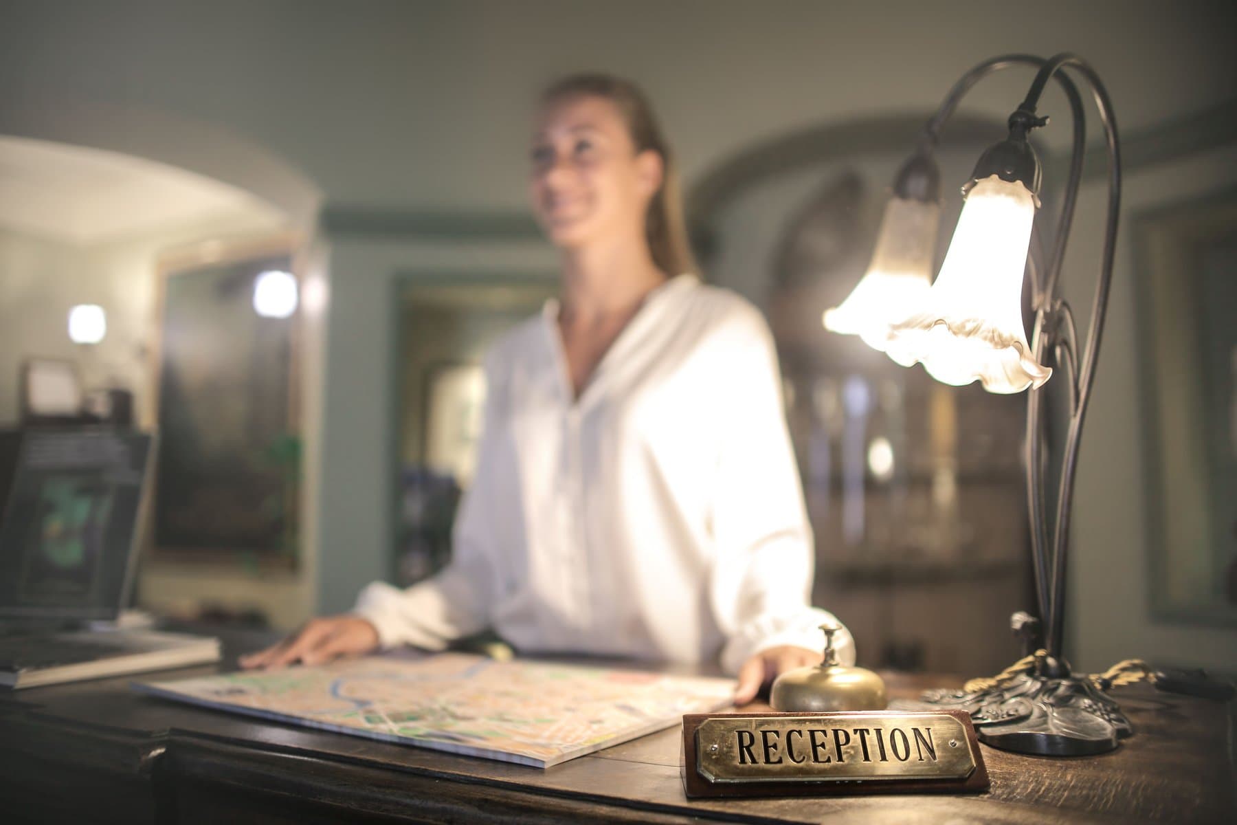 Il banco di una piccola reception d'albergo con targa in ottone, campanello e una piantina della città
