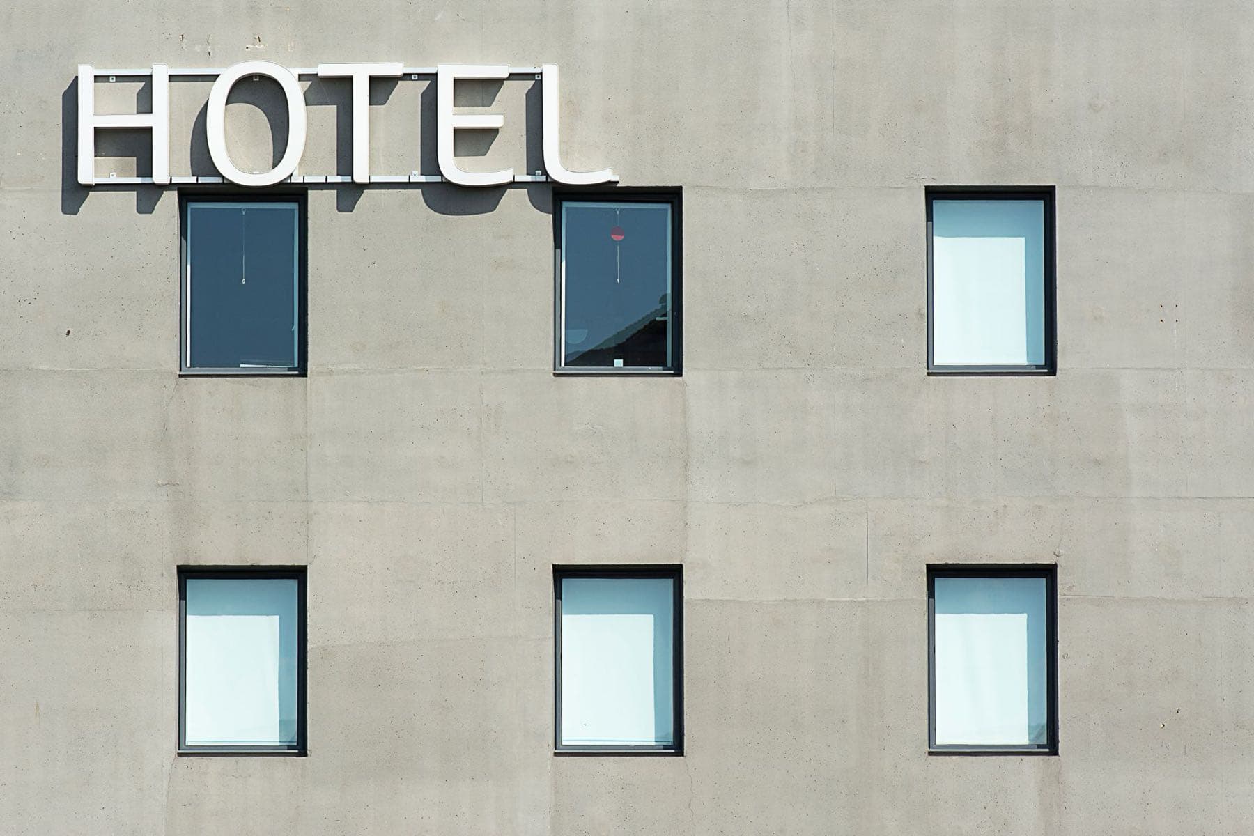 The HOTEL sign on a hotel's concrete façade, with the guest-room windows below